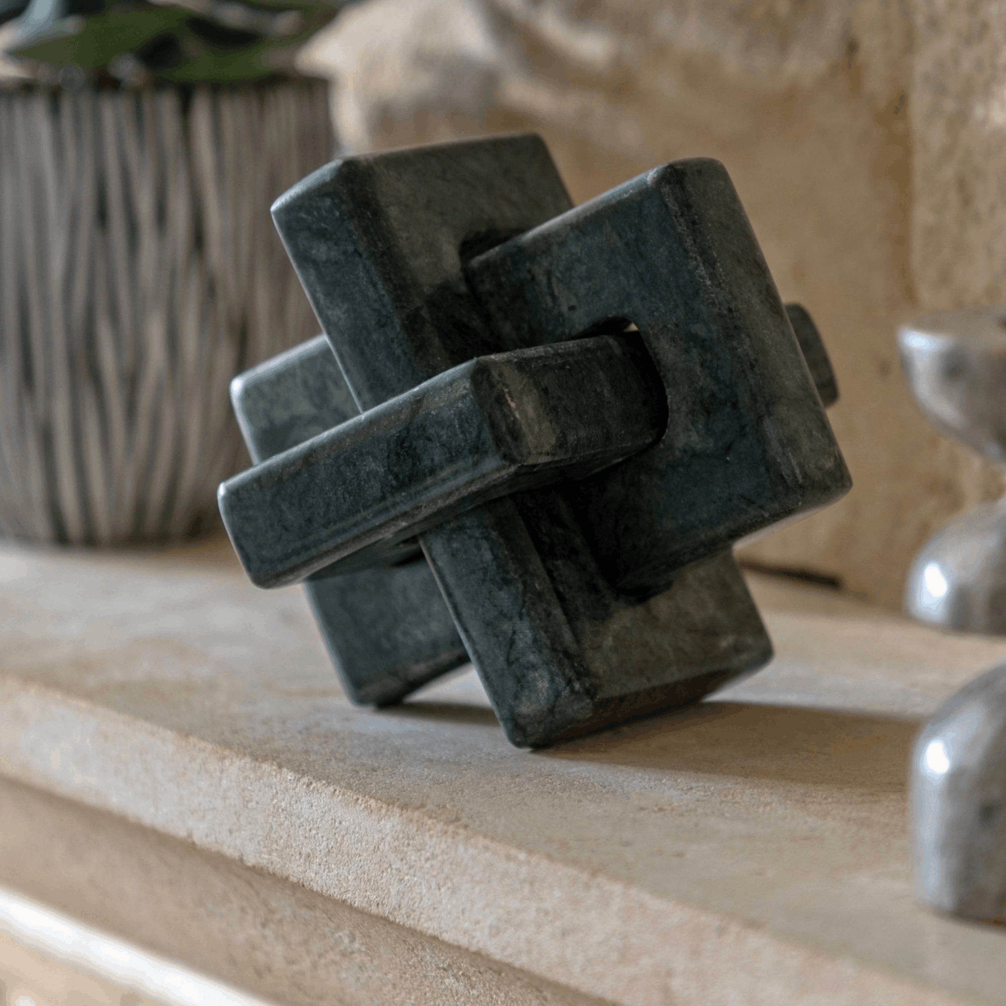 Luxury green marble sculpture with an interlocking square design, hand carved to bring texture and elegance to modern interiors.