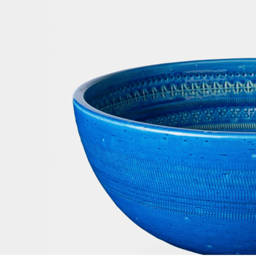 A close-up of a vibrant blue textured ceramic bowl on a light gray background.