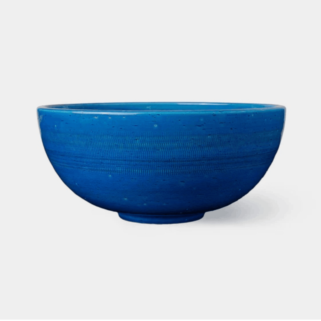 A vibrant blue ceramic bowl with a textured, speckled glaze, shown against a plain light gray background.