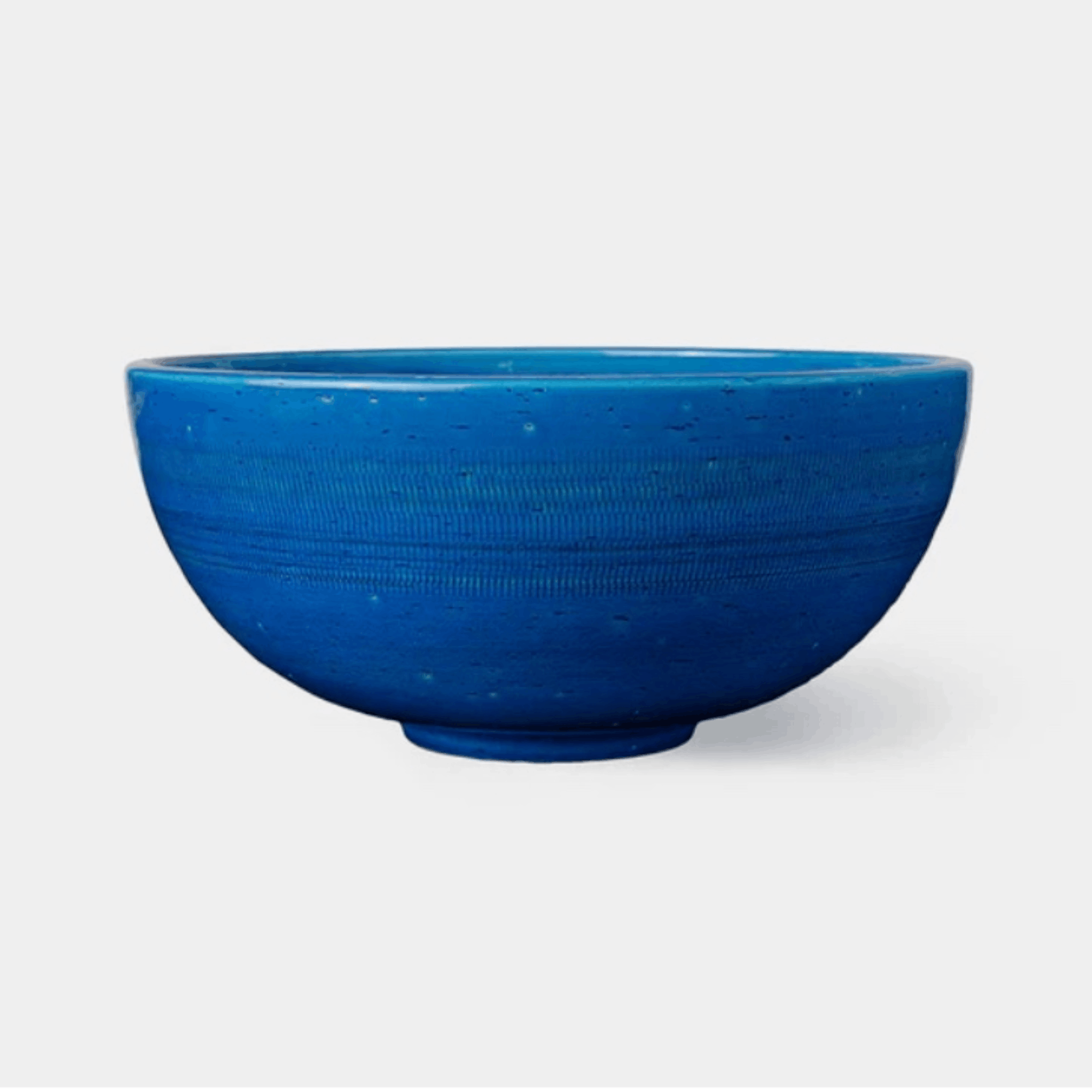A vibrant blue ceramic bowl with a textured, speckled glaze, shown against a plain light gray background.