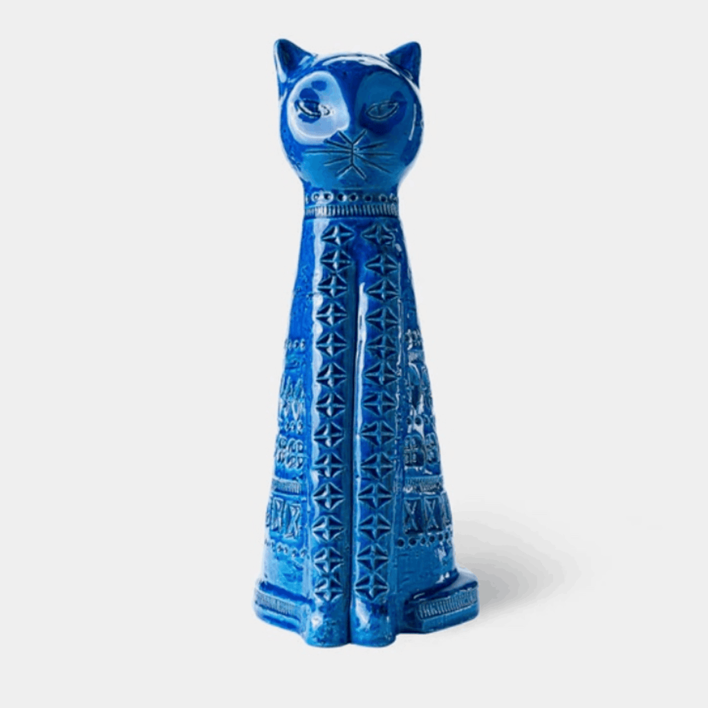 A glossy blue ceramic cat figurine with carved geometric patterns, standing upright against a light gray background.