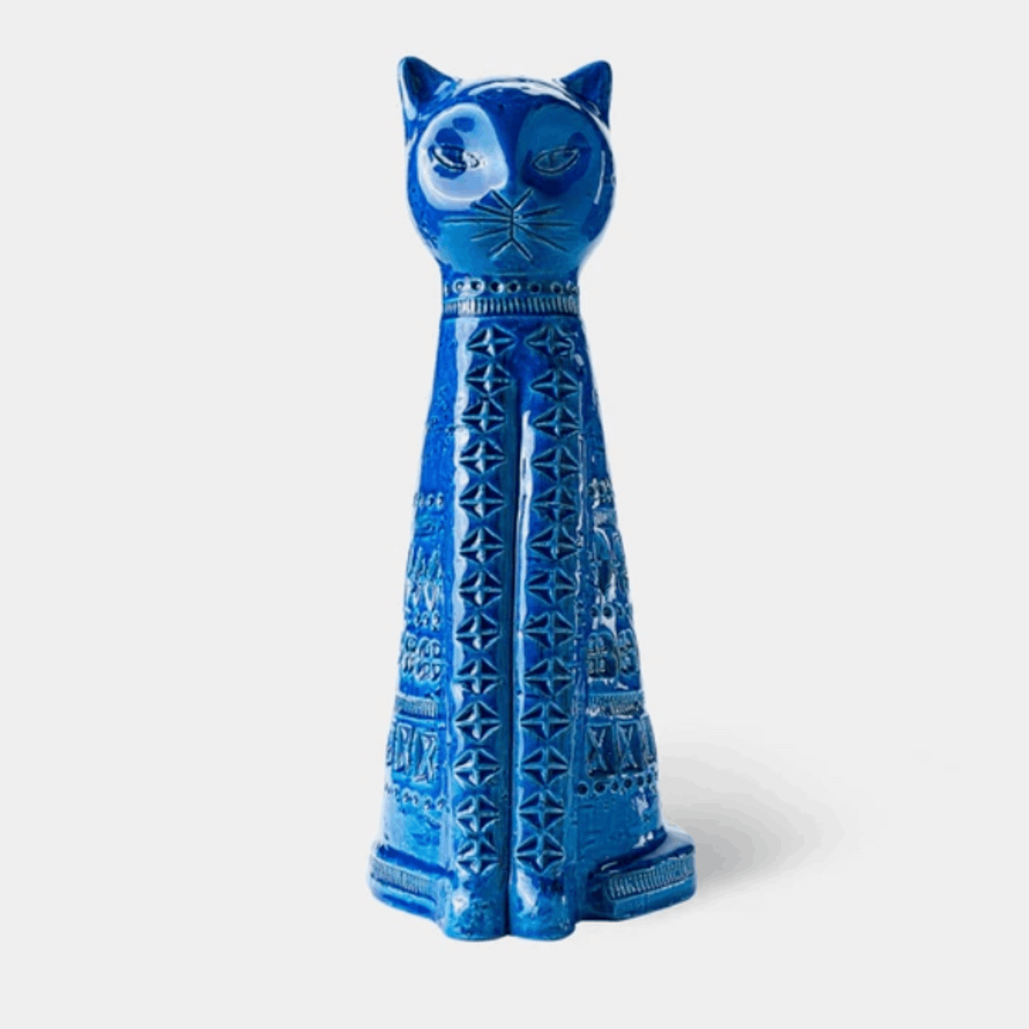 A glossy blue ceramic cat figurine with carved geometric patterns, standing upright against a light gray background.