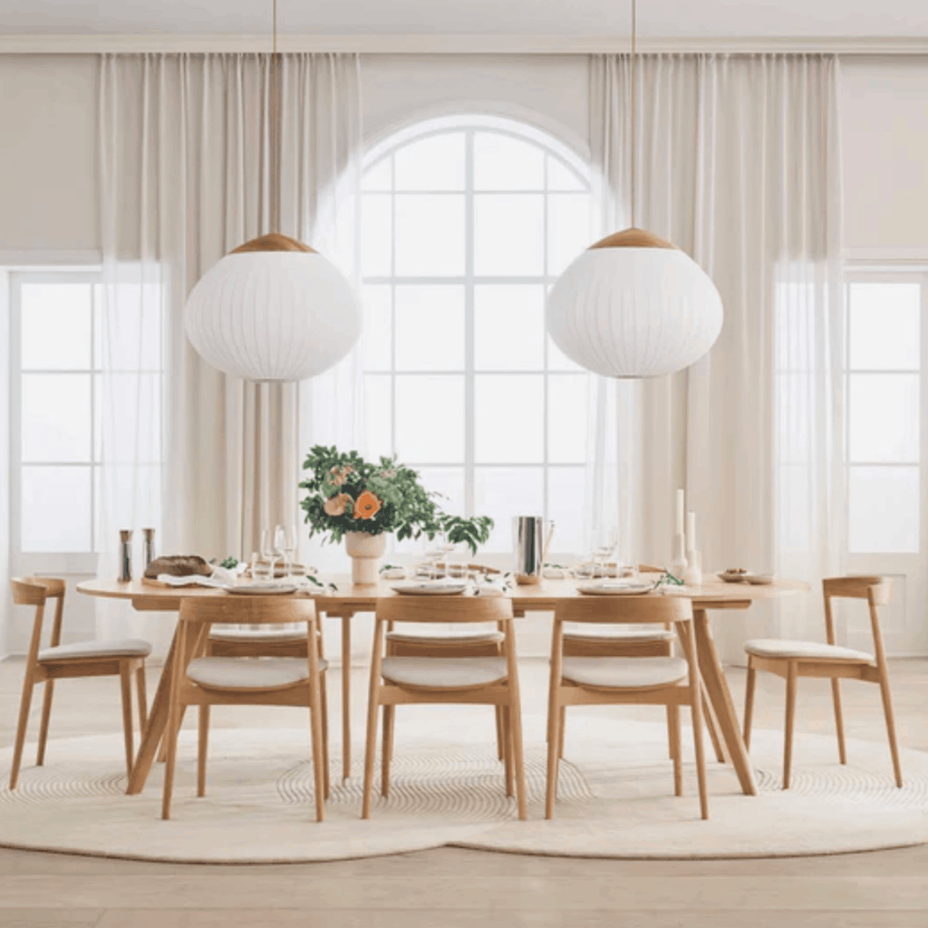 Dining room with wooden table and chairs on a Bolia Zen rug, large windows, and pendant lights.
