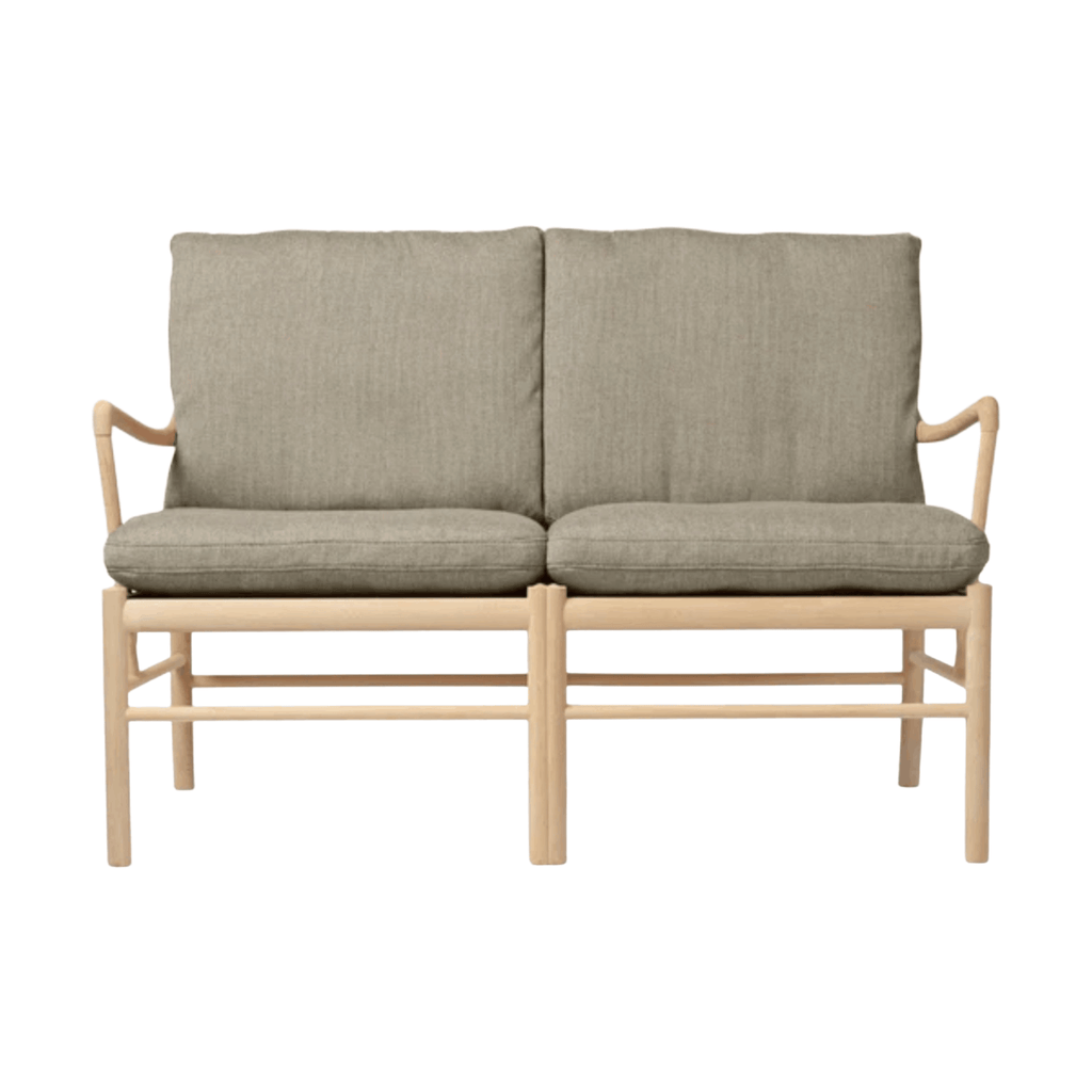 Two-seater sofa with beige frame and green cushions on a white background