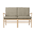 Two-seater sofa with beige frame and green cushions on a white background