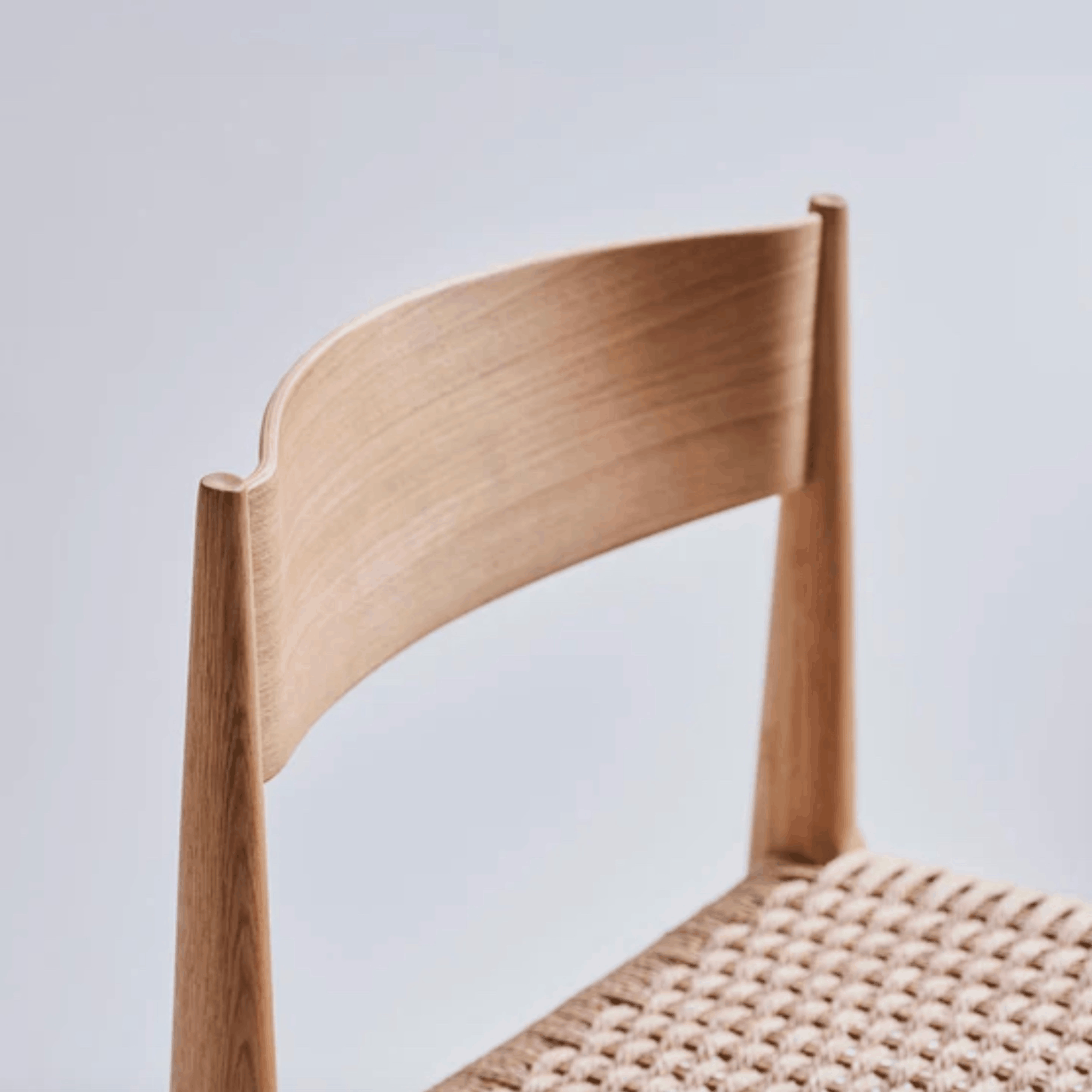 Wooden chair with woven seat on a light gray background