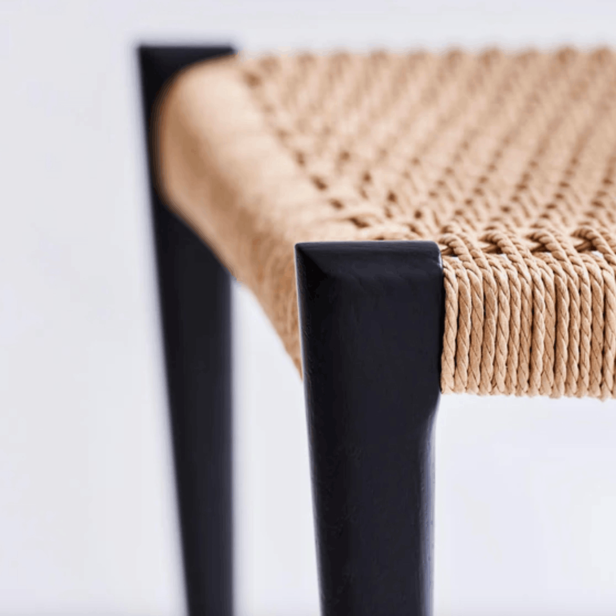 Close-up of a chair with woven seat and black wooden legs on a white background