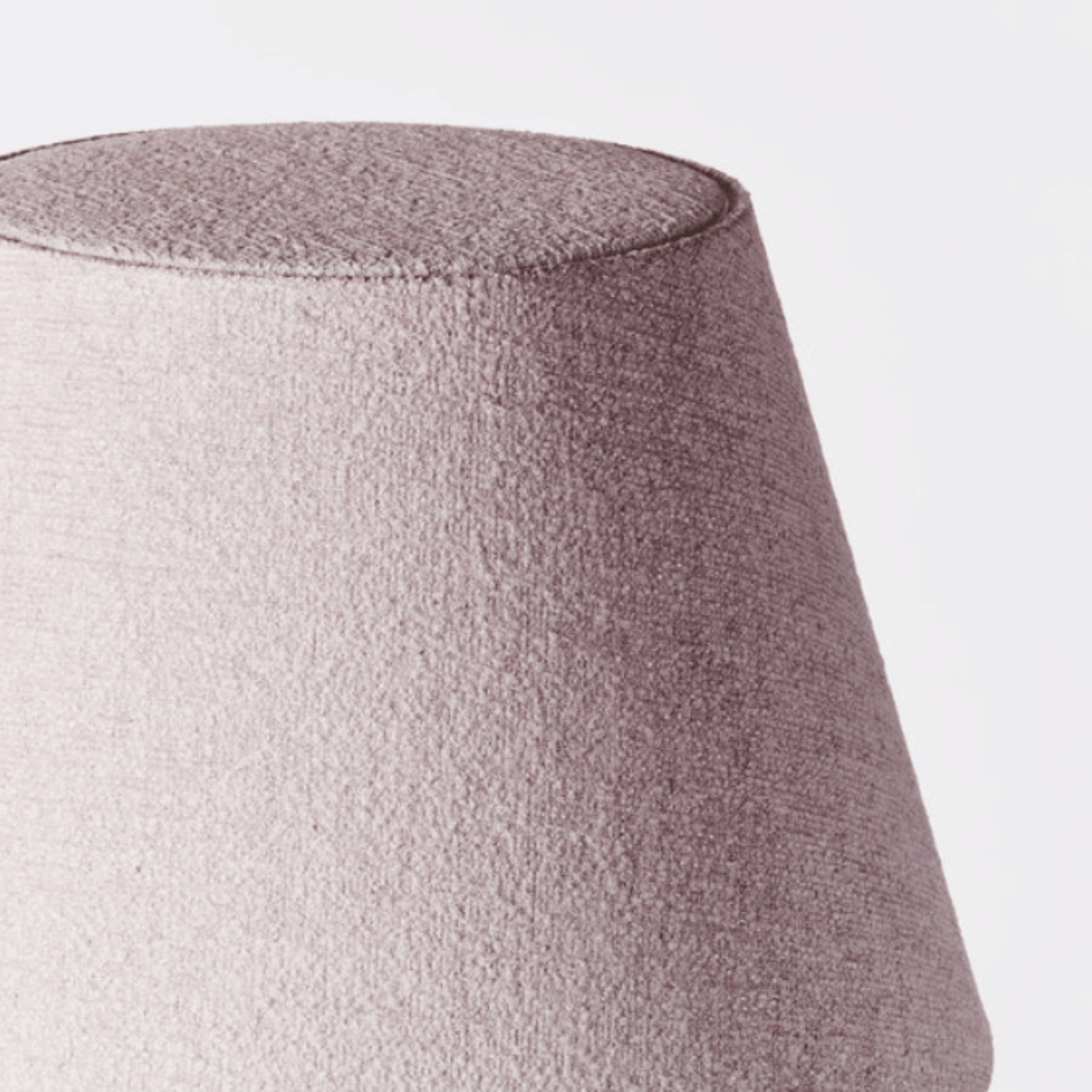 Close-up of a tapered fabric lampshade in a dusty mauve-pink textured fabric against a plain white background.