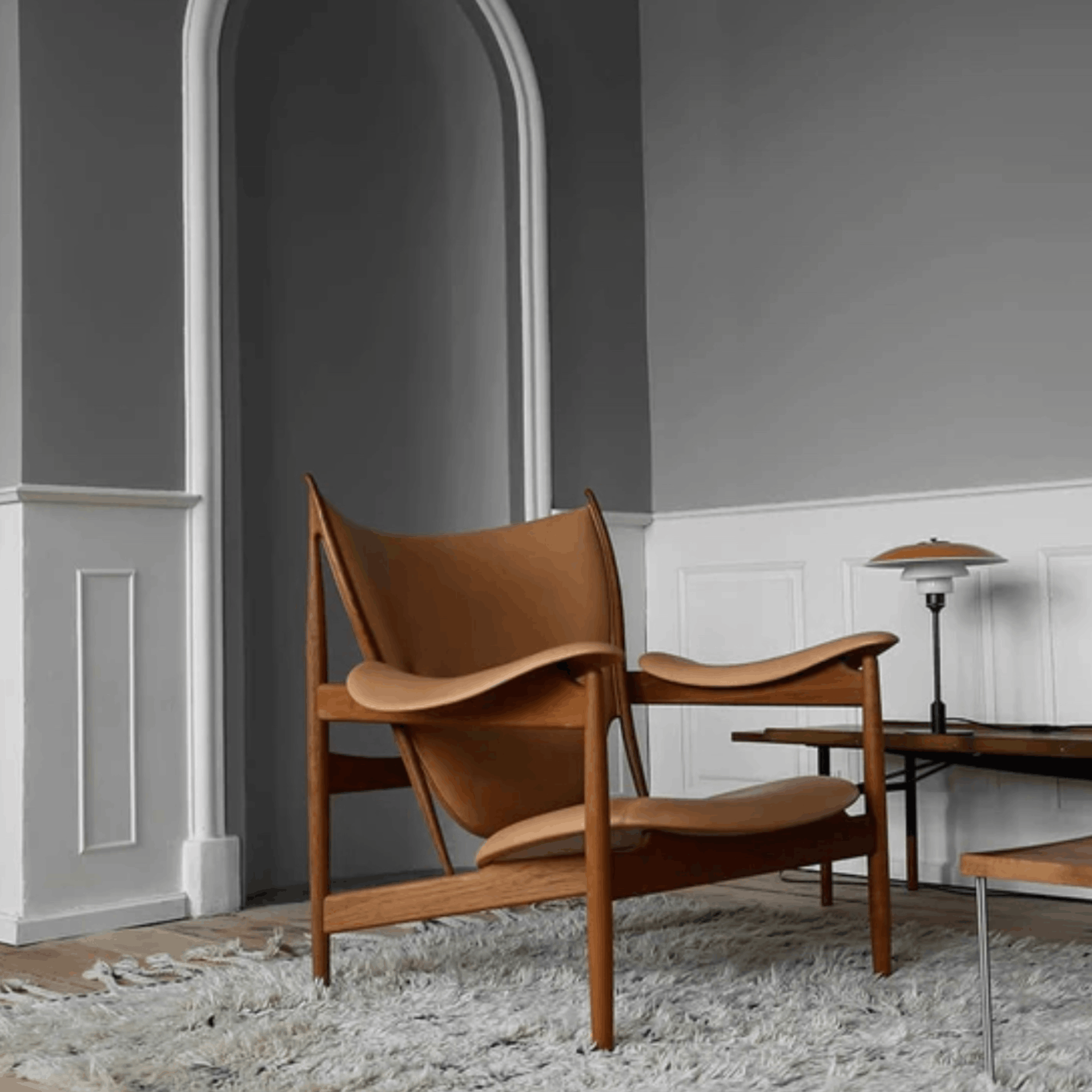 Brown leather chair in a modern room with gray walls and a white archway.