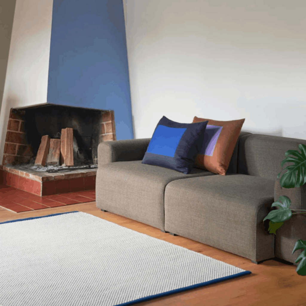 Contemporary wool rug by HAY in a living room setting with a sofa and fireplace.