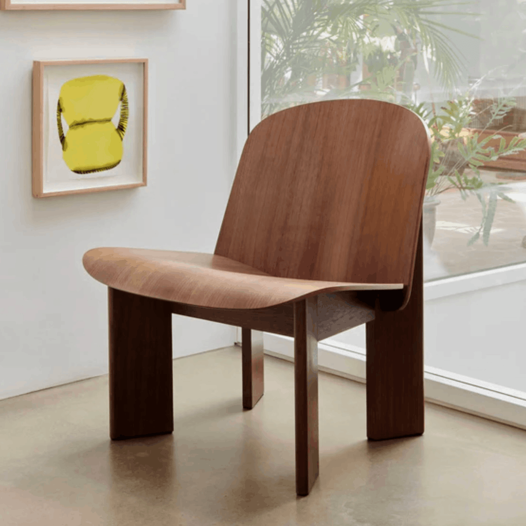 Wooden chair in a room with a yellow framed picture on the wall.