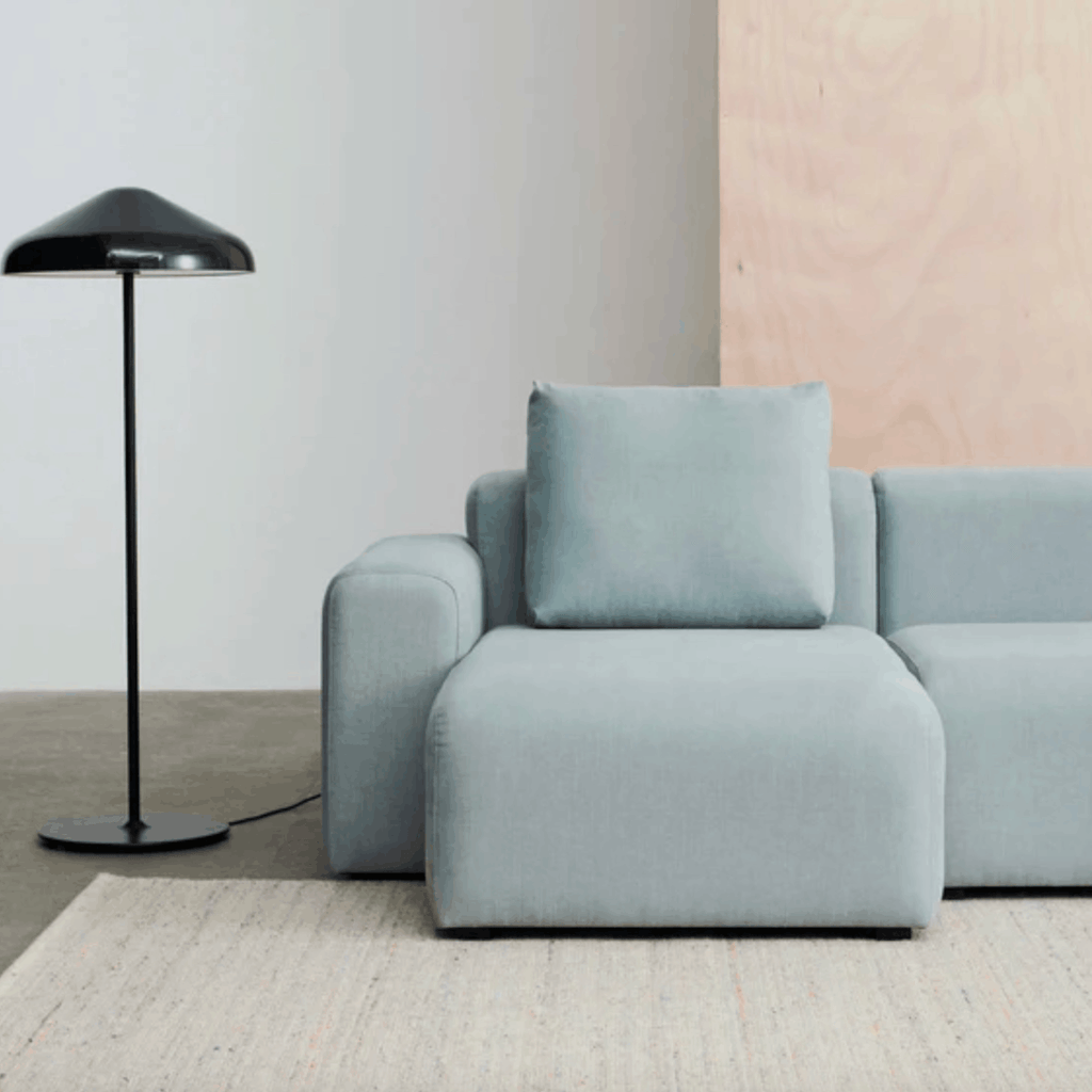 Light gray sofa on a Hays Crayon effect rug, with a black floor lamp in a minimalistic room.