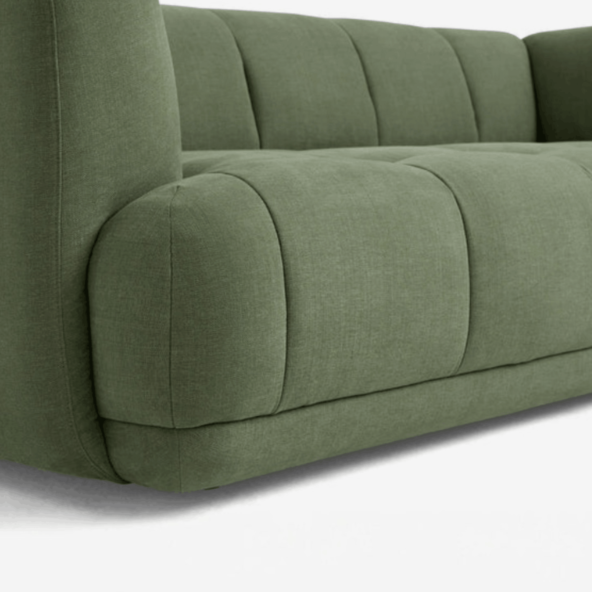 Close-up of a modern upholstered sofa in a muted sage green fabric, showing the tufted backrest and armrest details against a clean white background.