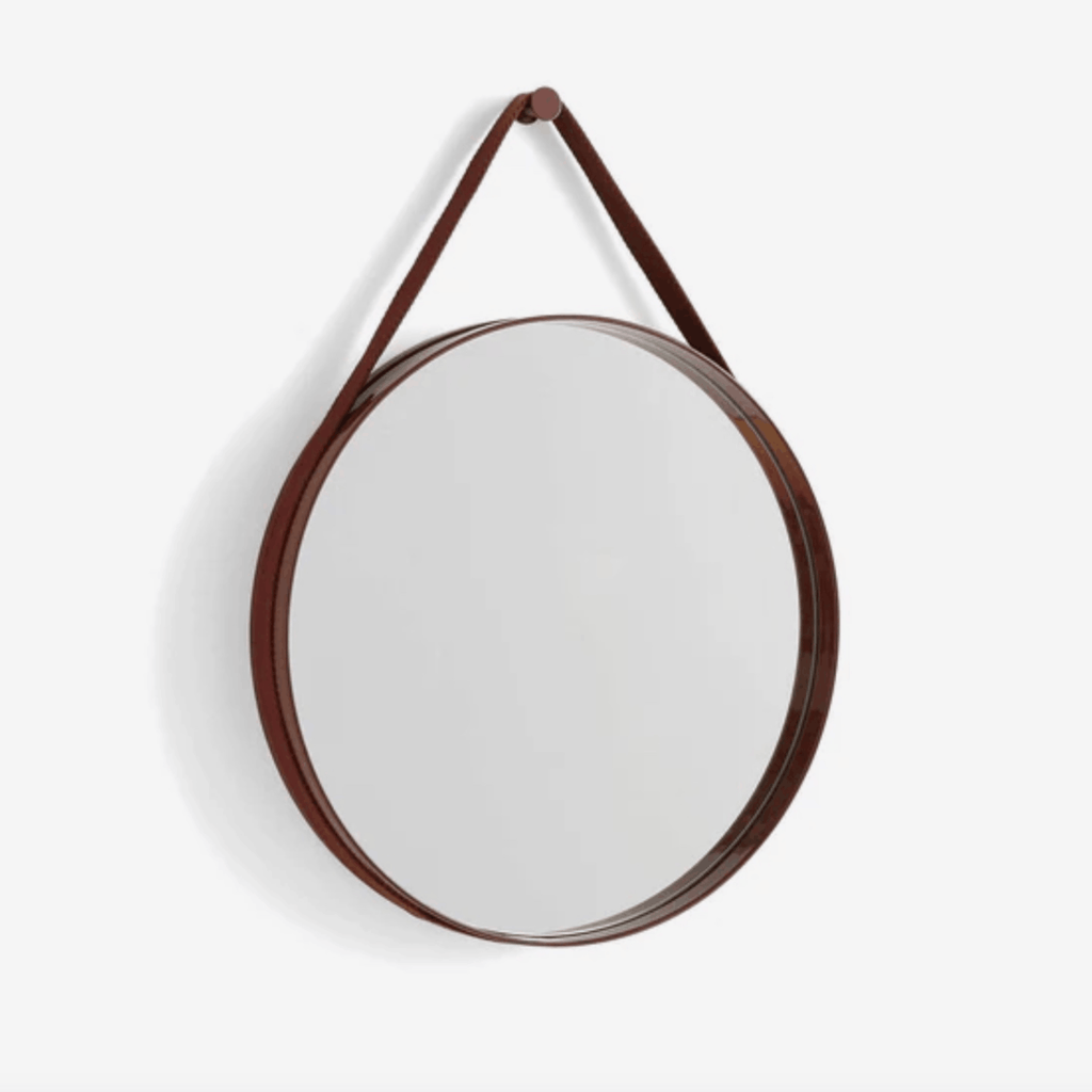 A contemporary round wall mirror by HAY featuring a minimalist steel strap design, perfect for bedrooms, bathrooms, and hallways.