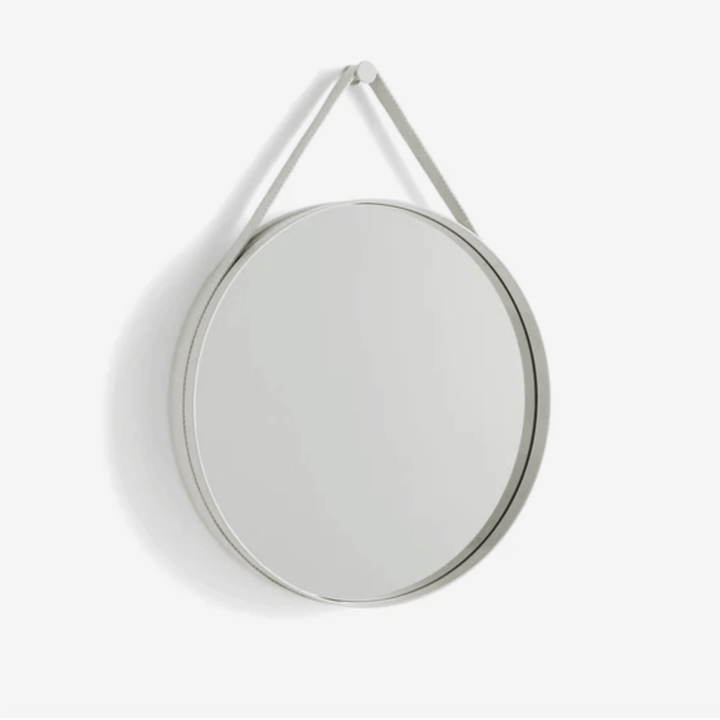A contemporary round wall mirror by HAY featuring a minimalist steel strap design, perfect for bedrooms, bathrooms, and hallways.