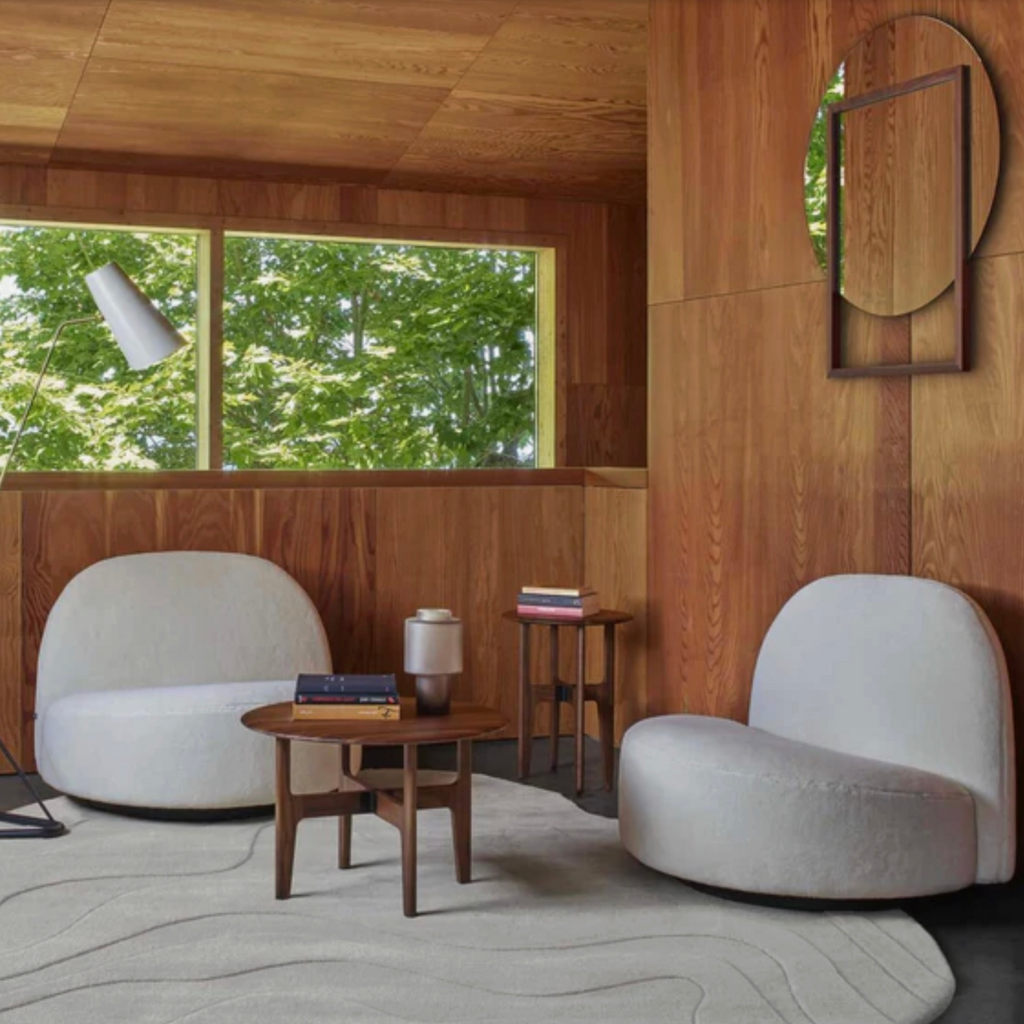 Modern interior with wooden walls, a window view of greenery, and two white chairs on a Ligne Roset Gavrinis rug in beige