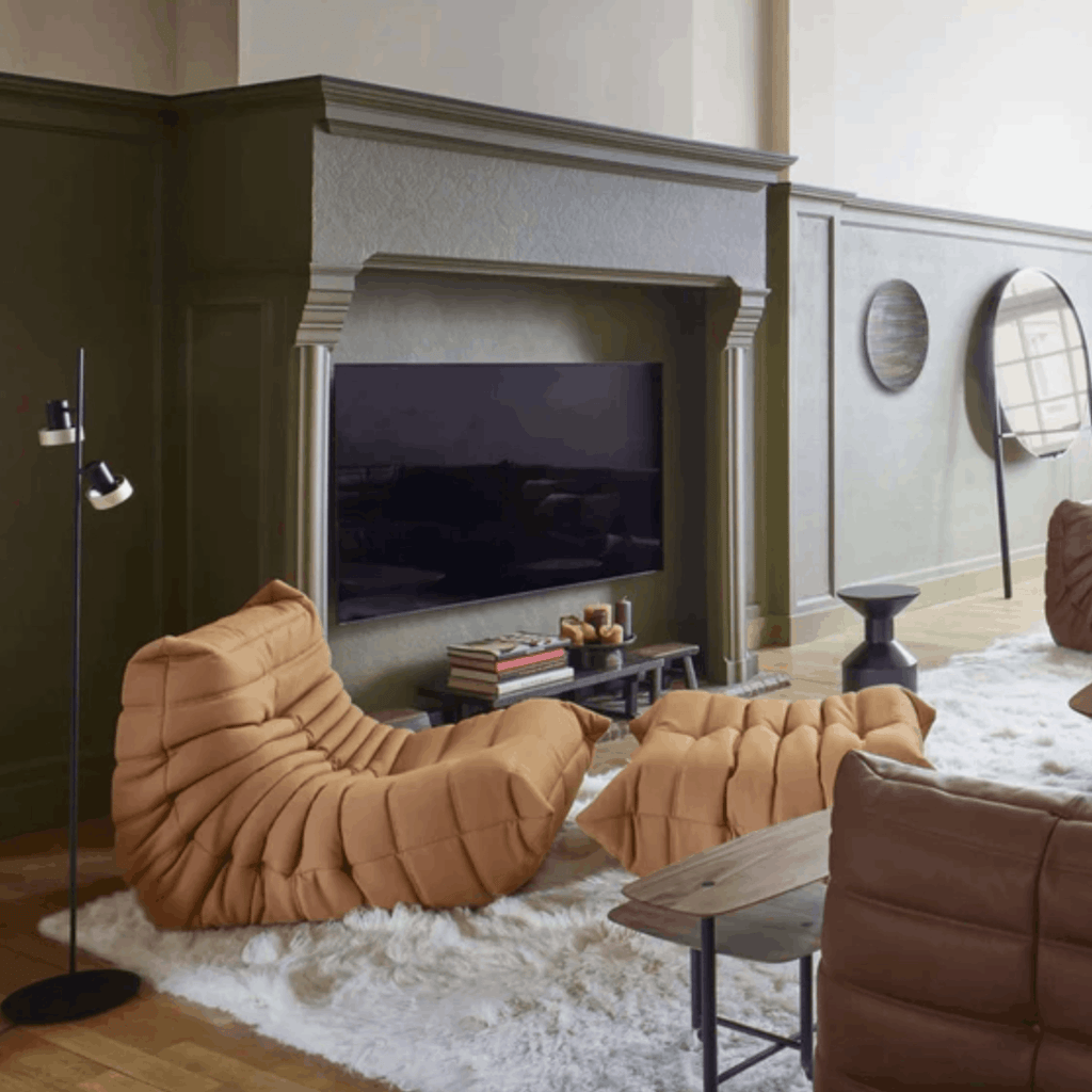 Modern living room with brown lounge chairs, a TV, and decorative items.