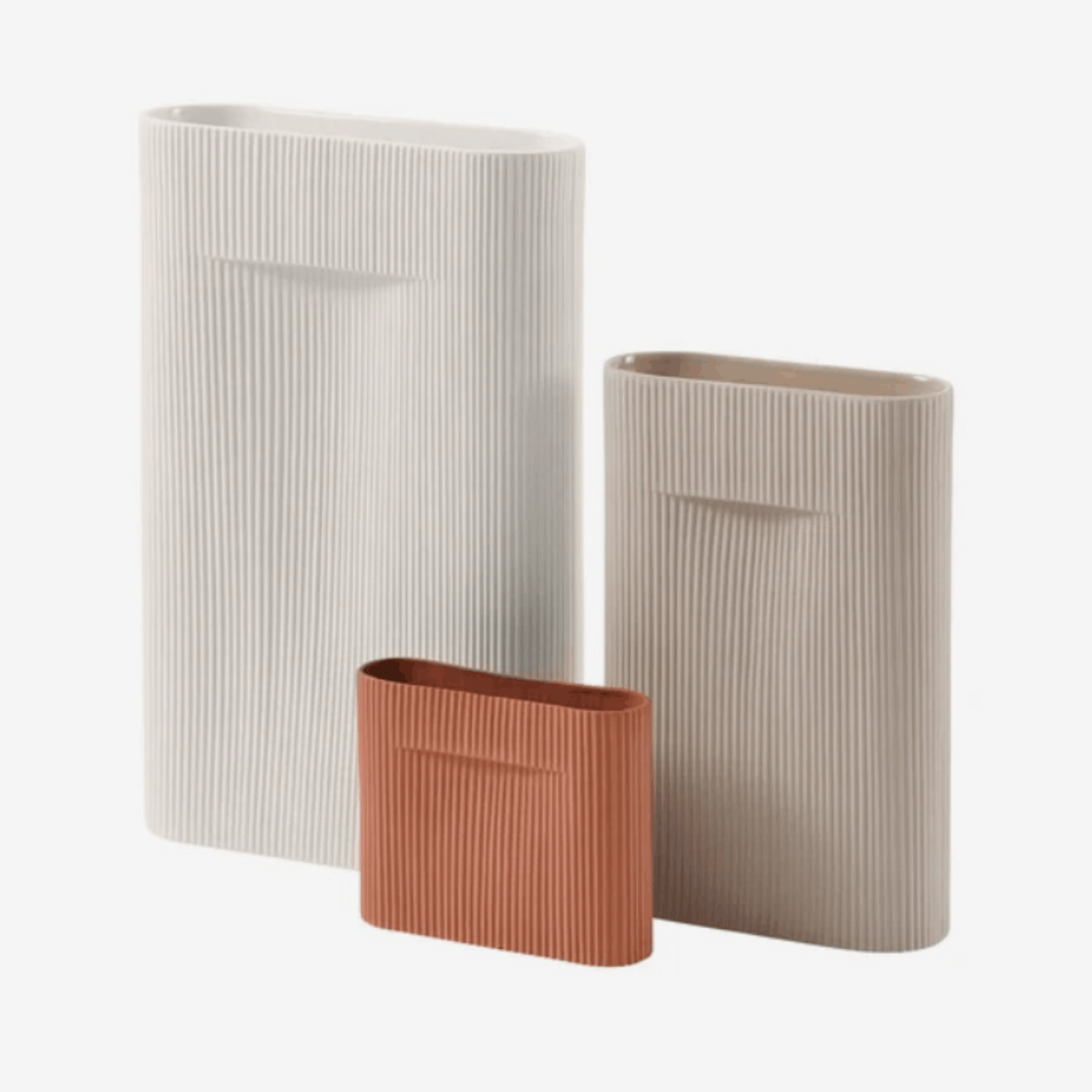Three ribbed ceramic vases in off-white, beige, and terracotta, arranged on a light gray background.
