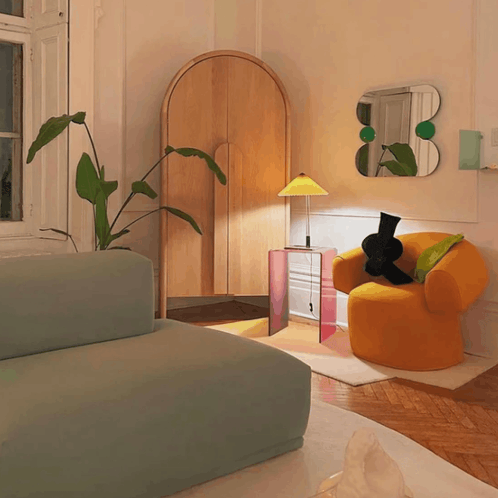 The Ready To Hang Squeeze Mirror hanging on a white above a modern beige sofa in a contemporary living room at dusk.