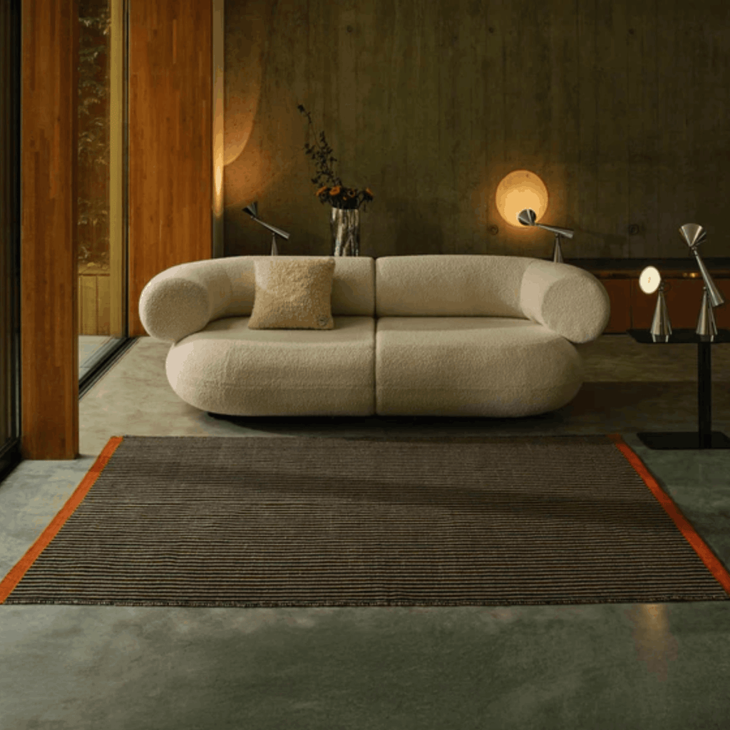 Modern beige sofa in a stylish room with a  Tom Dixon Line rug and decorative elements.