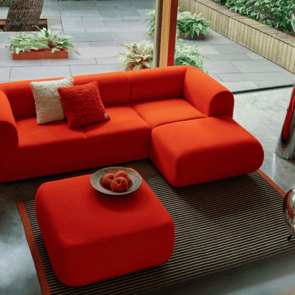 Orange sectional sofa with cushions on a Tom Dixon line rug.