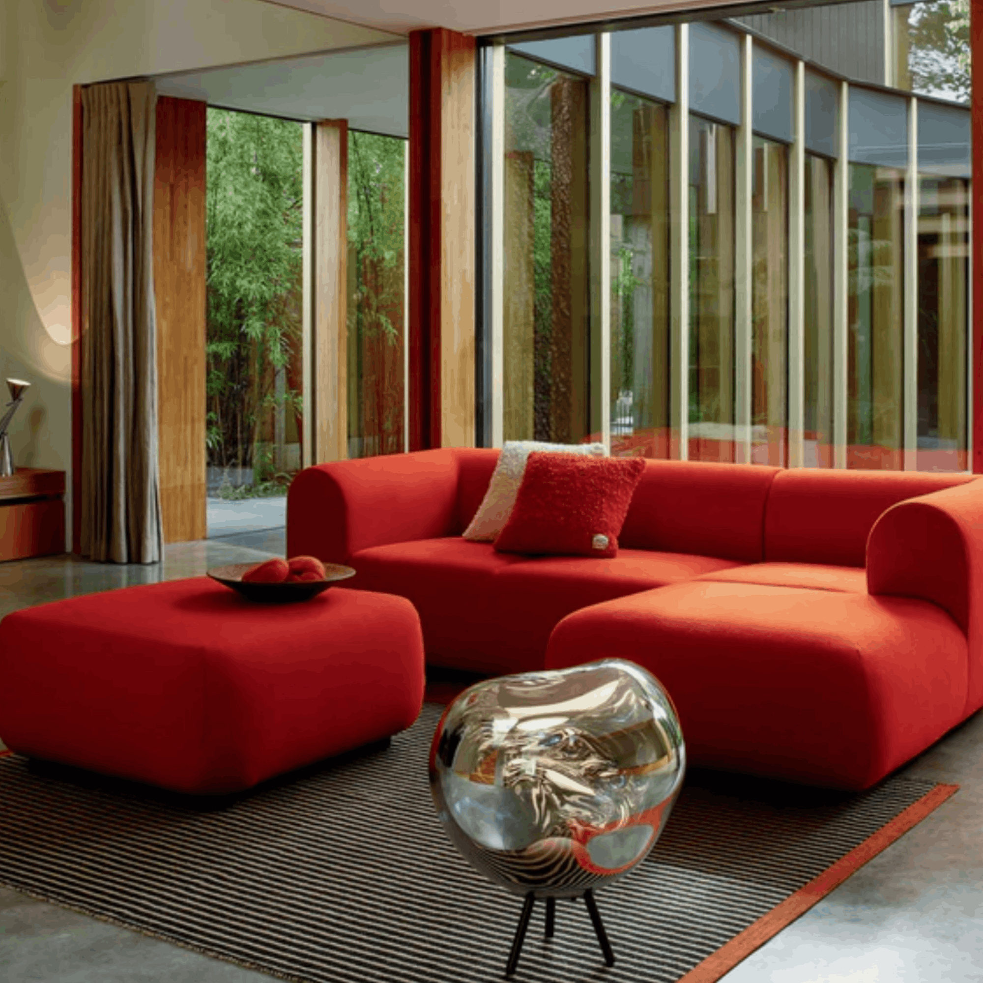 Modern living room with a red sectional sofa and ottoman on a Tom Dixon line rug.