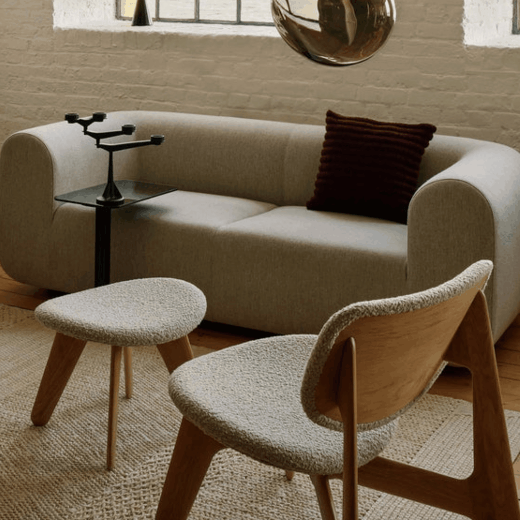 Modern living room with beige sofa, wooden chair, ottoman & Tom Dixon Cushion